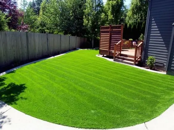 Garten mit grünem Rasen und Holzzaun